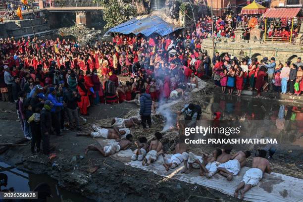 Hindu devotees offer prayers by rolling on the ground before performing a bathing ritual on the last day of the month-long 'Madhav Narayan' Hindu...
