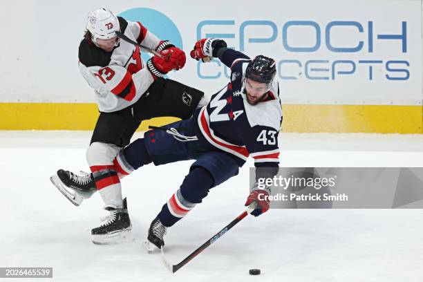 Tom Wilson of the Washington Capitals is checked by Tyler Toffoli of the New Jersey Devils during the first period at Capital One Arena on February...