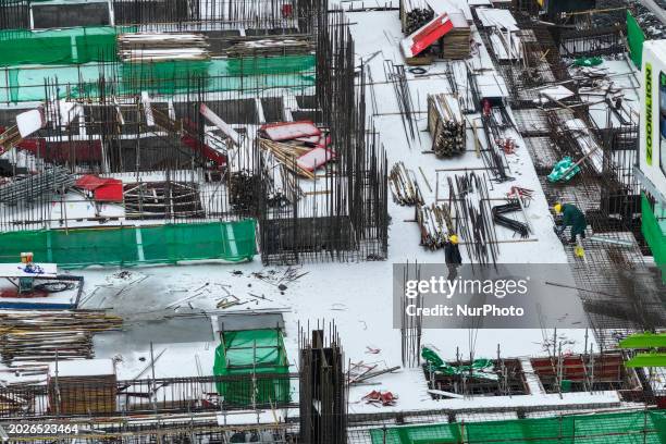 Workers are working at a building construction site as snow is falling in Nanjing, China, on February 24, 2024.