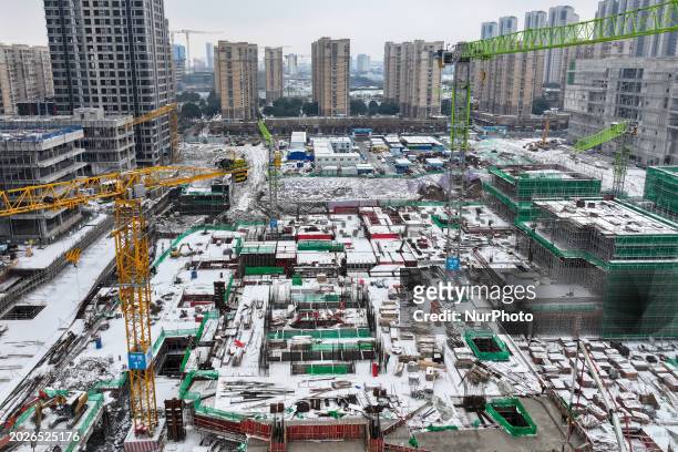 Workers are working at a building construction site as snow is falling in Nanjing, China, on February 24, 2024.