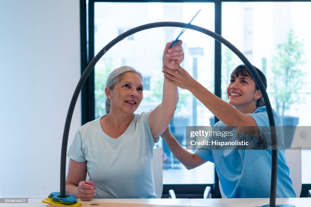 Cheerful senior woman in occupational therapy moving pieces from one side to another with the help of her therapist