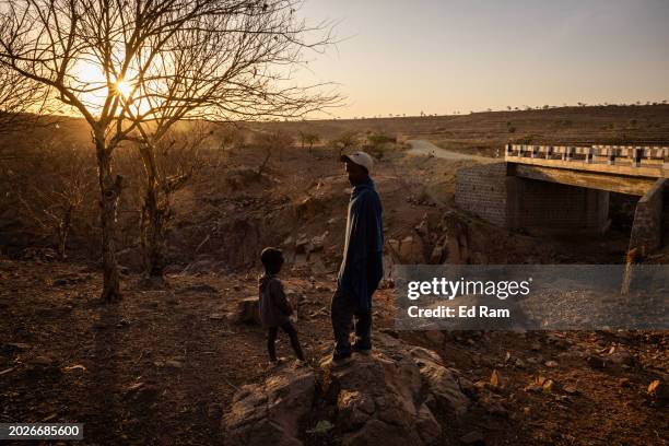 Farmer Gidey Haregot and his son Semur Gidey looks over at a dried out river bed by his house that on the outskirts of Yechila town in the Yechila...