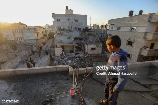 Boy stands atop a damaged building as others inspect damage to their homes following Israeli air strikes on February 21, 2024 in Rafah, Gaza. Strikes...