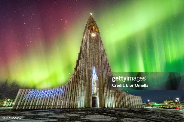 aurora boreal sobre la iglesia hallgrimskirkja en el centro de la ciudad de reikiavik, islandia - aguja chapitel fotografías e imágenes de stock