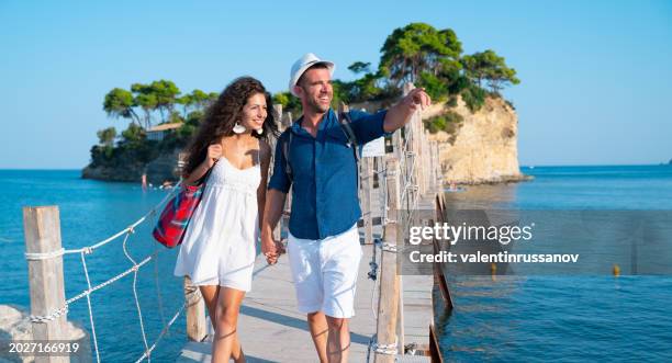 couple in love laughing while walking together in the waterfront in their vacation in zakynthos - greece holiday stock pictures, royalty-free photos & images