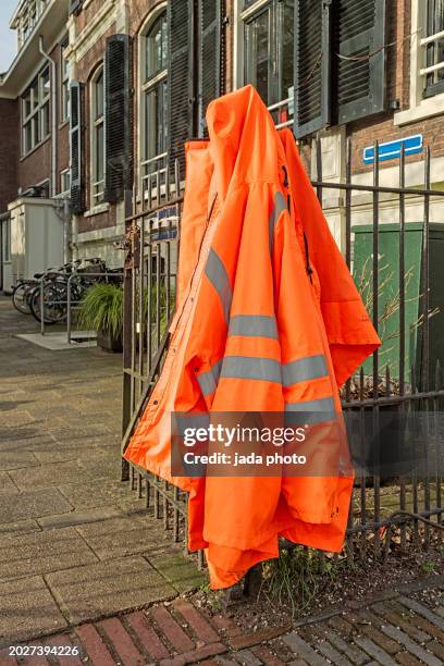 orange safety jackets hang outside on a steel fence - orange jacka bildbanksfoton och bilder