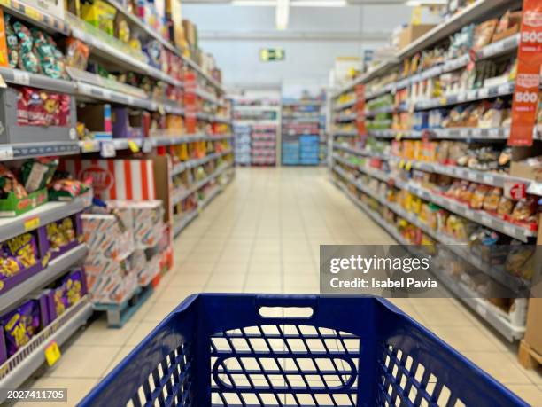 an empty trolley at supermarket corridor - super market stock pictures, royalty-free photos & images