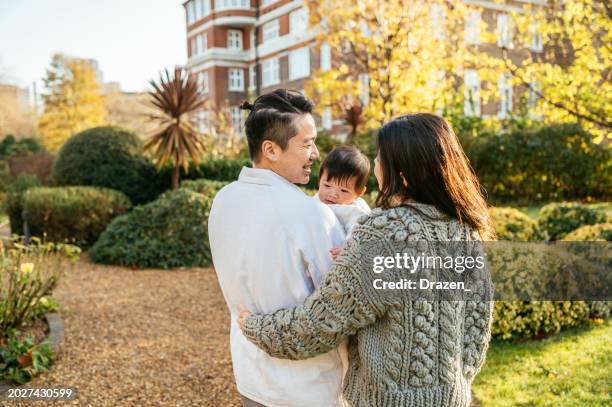 chinese family with baby walking in park, couple holding baby and enjoying sunny day - family life stock pictures, royalty-free photos & images