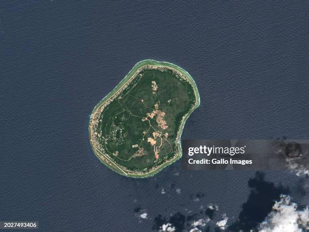 In this satellite image, Nauru, a tiny island nation in the Pacific Ocean, lies northeast of Australia and northwest of Tuvalu, known for its...