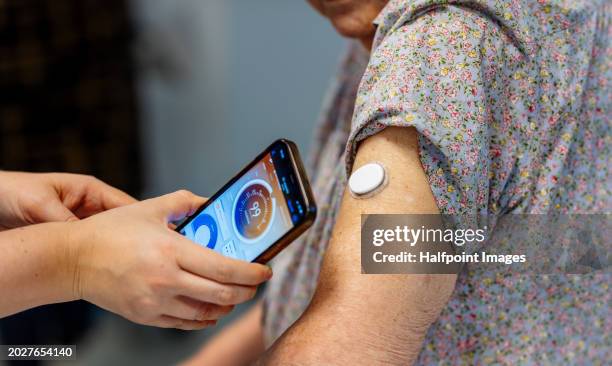 diabetologist teaching senior patient how to connect smartphone to the continuous glucose monitor. - glucose stockfoto's en -beelden