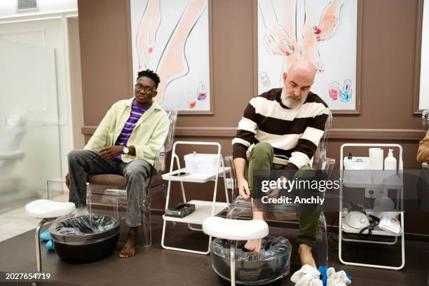 men doing pedicure in a beauty salon - black painted toes stock pictures, royalty-free photos & images