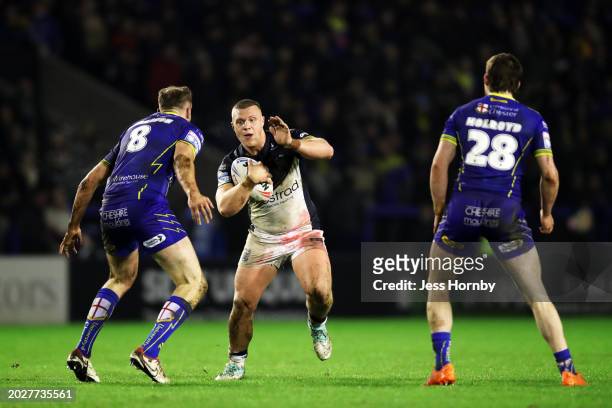 Jack Brown of Hull FC runs with the ball whilst under pressure from James Harrison and Adam Holroyd of Warrington Wolves during the Betfred Super...