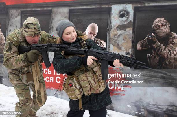An officer of Russian Federal Security Service FSB teaches a boy to shoot a Kalashnikov assault rifle during a pro-military event, called "The...