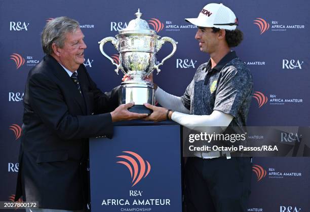 Altin Van Der Merwe of South Africa is presented with the trophy by Leopard Creek Chairman Johann Rupert following his victory in a playoff during...