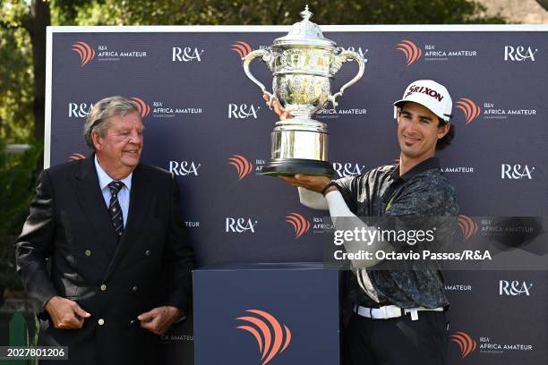 Altin Van Der Merwe of South Africa is presented with the trophy by Leopard Creek Chairman Johann Rupert following his victory in a playoff during...