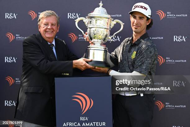 Altin Van Der Merwe of South Africa is presented with the trophy by Leopard Creek Chairman Johann Rupert following his victory in a playoff during...