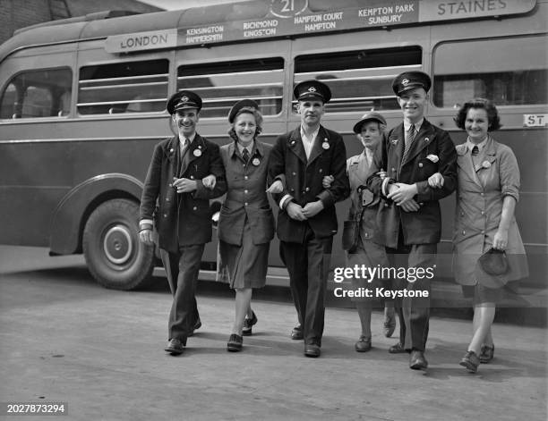 London Transport bus drivers and conductors, who are also married couples, the Hook, the Skilton, and the Lewis, walking together arms in arms,...