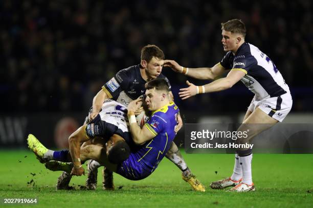 Josh Thewlis of Warrington Wolves is tackled by Fa'amanu Brown , Jordan Lane and Will Gardiner of Hull FC during the Betfred Super League match...