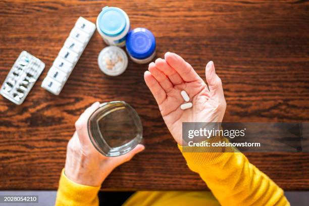 vista aérea de una mujer mayor que toma una píldora médica - circulatory system hand fotografías e imágenes de stock