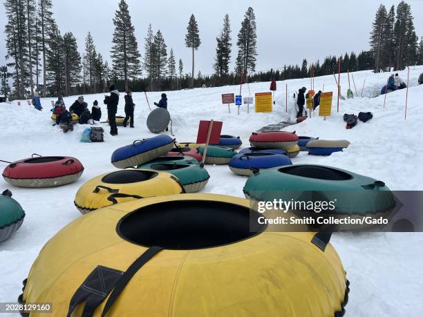 Winter fun with snow tubes ready for sliding on a snowy hill, with people enjoying the outdoors in the background, Soda Springs Road, Nevada County,...