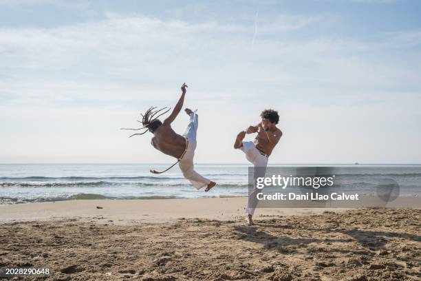 men train capoeira on the beach - kicking sand stock pictures, royalty-free photos & images