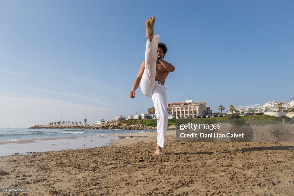 Ein Mann trainiert Capoeira am Strand.