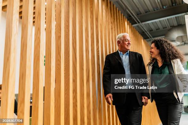 senior businessman walking and talking with employee at office - mannerism stock pictures, royalty-free photos & images