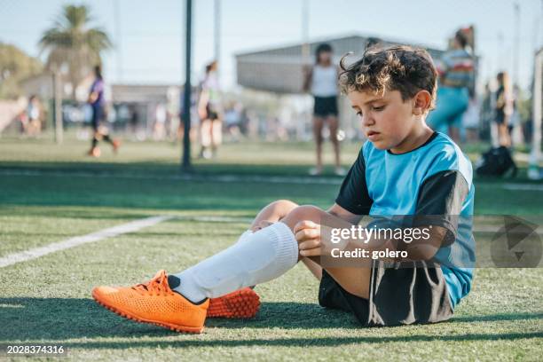 soccer boy rollibng up socks  after match - finals game one stock pictures, royalty-free photos & images