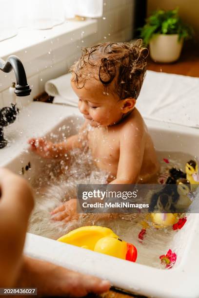 baby boy playing with  birth duck in the kitchen sink - dodge stock pictures, royalty-free photos & images