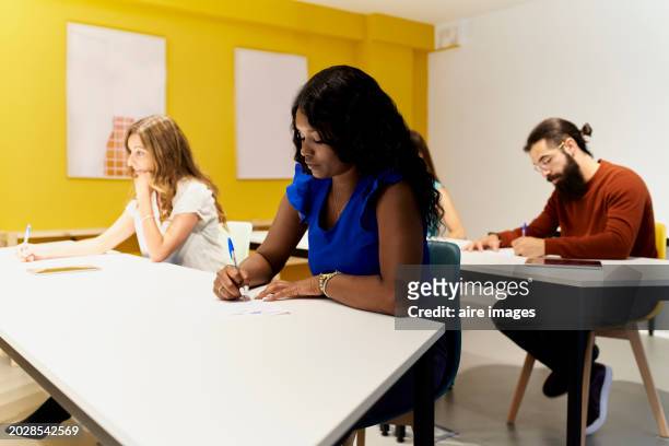 side view of a brunette woman sitting with a group of people coworkers sitting in a dining room in the office - brunette sitting at desk stock-fotos und bilder
