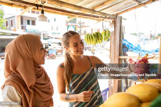 two young women one wearing a hijab buying dragon fruit in a rural town in thailand - tooth bonding stock pictures, royalty-free photos & images