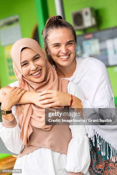 a smiling portrait of a young muslim woman and her friend outside her mosque in southern thailand - tooth bonding stock pictures, royalty-free photos & images