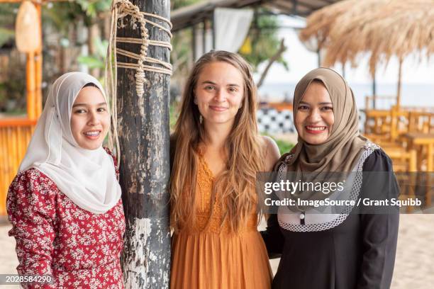 portrait of three women friends, two wearing hijab in a coastal town in southern thailand - tooth bonding stock pictures, royalty-free photos & images