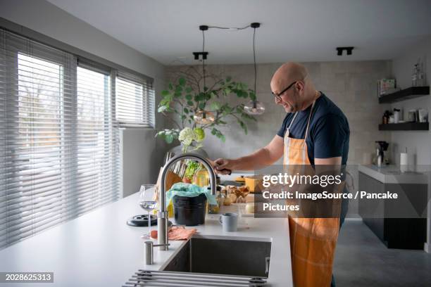 nederland - ui snijden  koken op inductie  man is in de keuken bezig met het maken van lasagnesaus  foto: patricia rehe / anp / hollandse hoogte - koken man stock-fotos und bilder