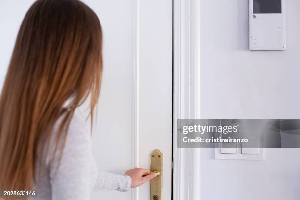 young woman opening the door of home - cristinairanzo stock pictures, royalty-free photos & images