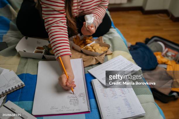 close-up of student's hand writing notes amidst fast food and a suitcase - chicken strip stock pictures, royalty-free photos & images