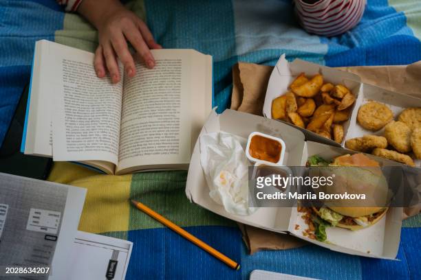 overhead view of a book, fast food, and study materials on a bed - chicken strip stock pictures, royalty-free photos & images