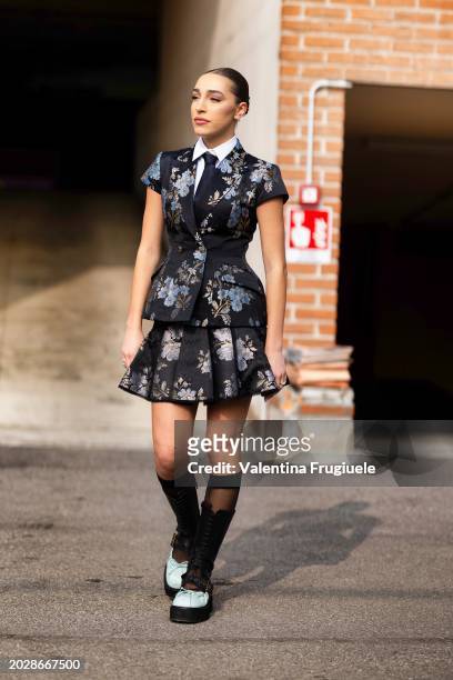 Ginevra Mavilla is seen wearing white and black platform ballerina shoes, black lace long socks, a white shirt, a black tie and a black printed...