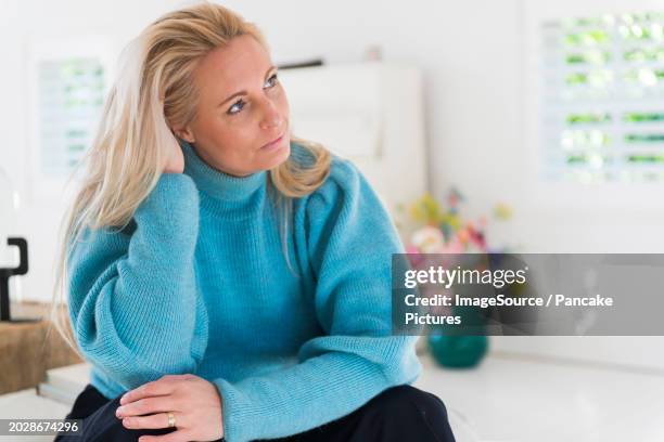 very attractive older blonde woman looking into camera for a portrait in her home - 40 44 years stock pictures, royalty-free photos & images