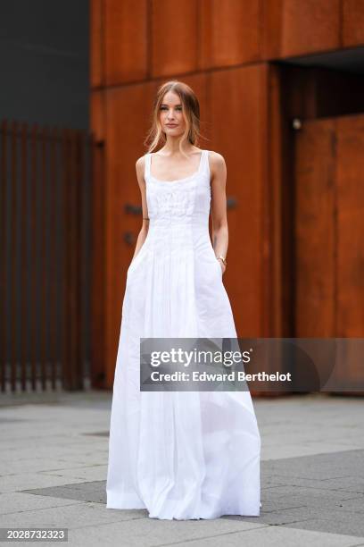 Victoria Magrath wears a white low-neck long sleeveless dress with gathered and embroidered parts, outside Alberta Ferretti, during the Milan Fashion...