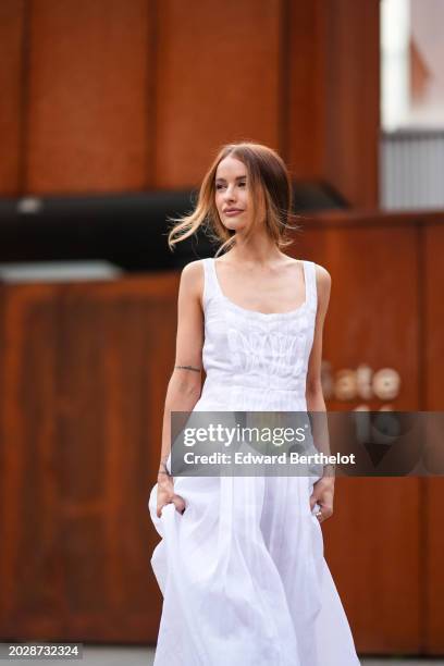Victoria Magrath wears a white low-neck long sleeveless dress with gathered and embroidered parts, outside Alberta Ferretti, during the Milan Fashion...