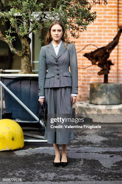 Michela d'Angelo is seen wearing a black leather bag, black pumps, a white shirt and a checked grey jacket with the matching long skirt outside...