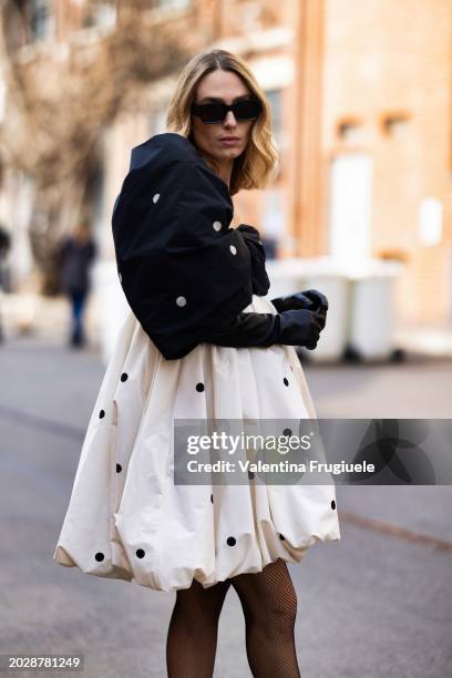 Guest is seen wearing black sunglasses, black fishnet tights, black leather long gloves and a white and black asymmetrical one-shoulder polka printed...