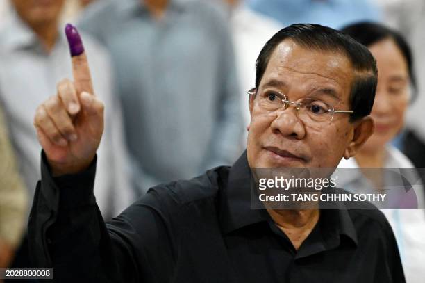Member of parliament and Cambodia's former prime minister Hun Sen shows his inked finger after voting at a polling station during the Senate election...