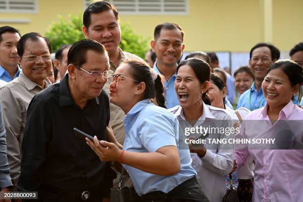 Member of parliament and Cambodia's former prime minister Hun Sen receives a kiss from a commune councillor after he cast his vote at a polling...