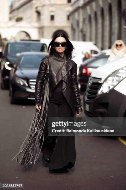 Amelie Stanescu wears white black pants, a black leather jacket, and a black bag with tassels outside Onitsuka Tiger during the Milan Fashion Week -...