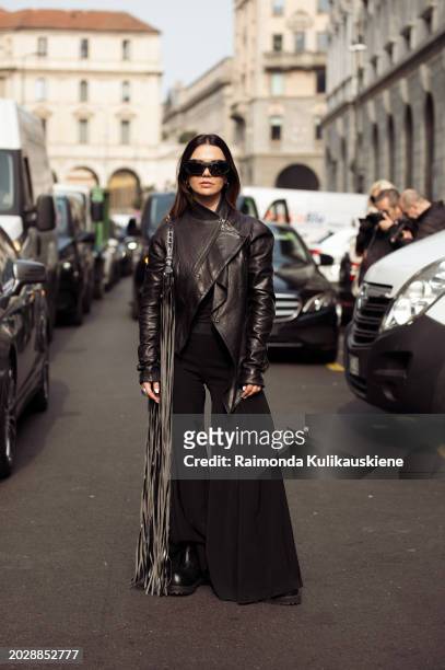 Amelie Stanescu wears white black pants, a black leather jacket, and a black bag with tassels outside Onitsuka Tiger during the Milan Fashion Week -...