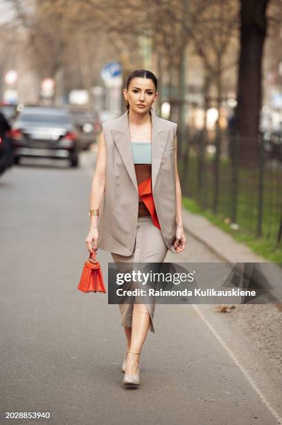 Alexandra Pereira wears grey shoes, a grey sleeveless vest, a midi skirt with slit, a red bag, and a brown blue off-shoulder top outside Fendi during...