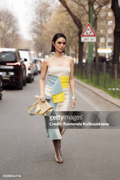 Heart Evangelista wears off shoulder beige blue-yellow dress with a slit, matching colors bag, and animal print ankle boots outside Fendi during the...