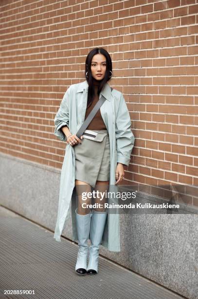 Yoyo Cao wears a pale green skirt, blue coat, brown top, and blue boots outside Fendi during the Milan Fashion Week - Womenswear Fall/Winter...